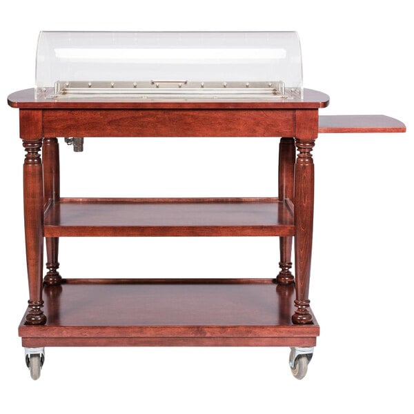 A Bon Chef mahogany cheese cart with wheels and a clear cover.