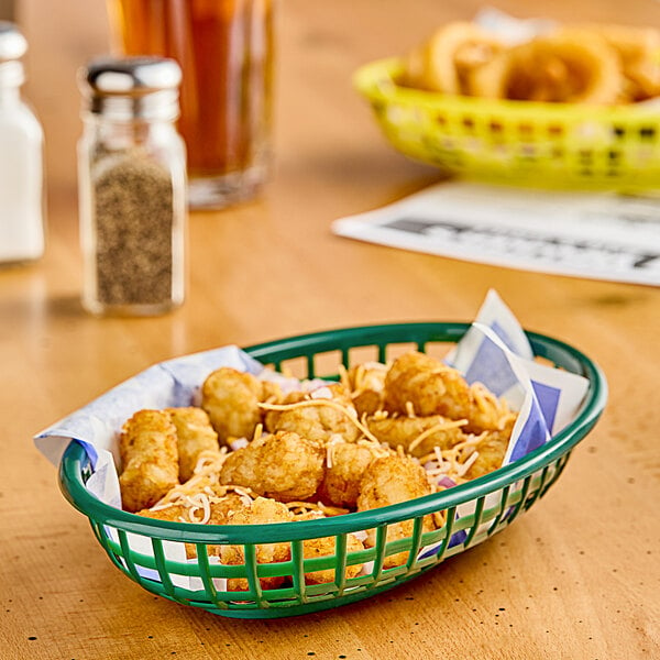 A forest green plastic oval fast food basket filled with tater tots.