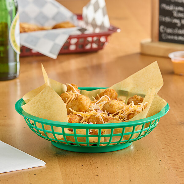 A green plastic fast food basket filled with nachos on a table in a restaurant.