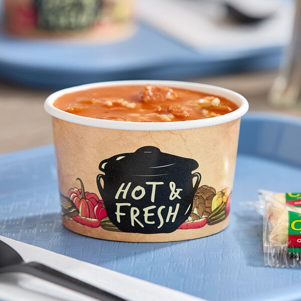 A white Choice double poly-coated paper soup container filled with soup on a plate.