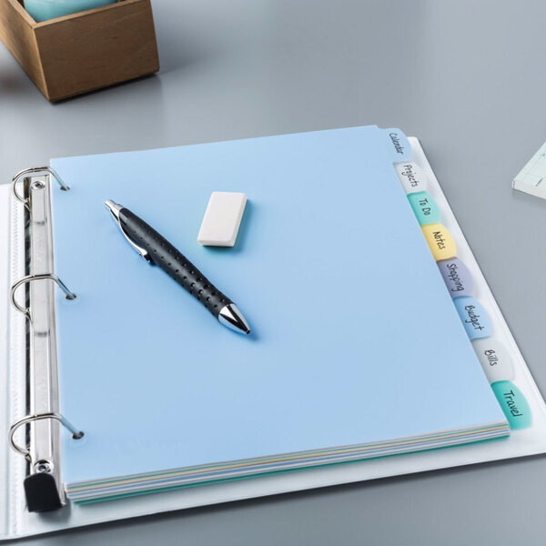 A white file folder with colorful tabs on a blue surface with a pen and eraser.