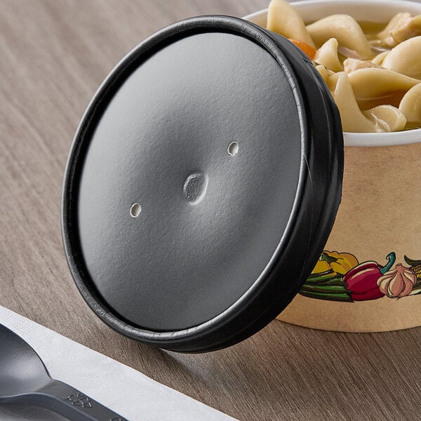 A black container of noodles with a vented lid.