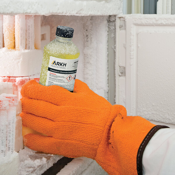 A person wearing orange gloves using Avery UltraDuty GHS labels to label a bottle of liquid.