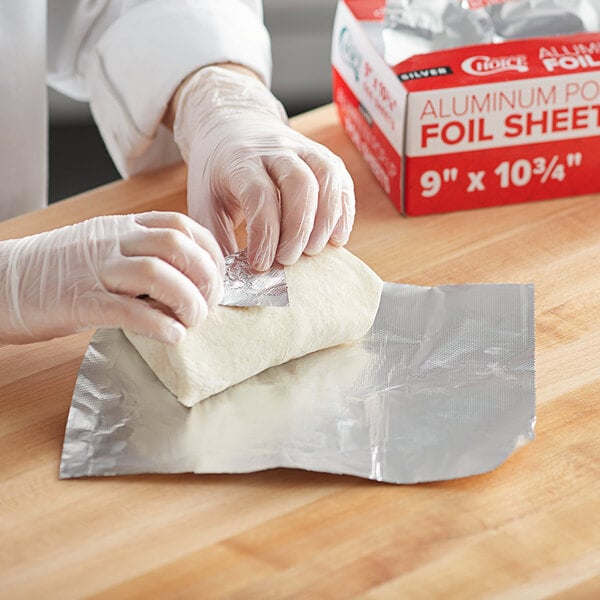 A person in gloves wrapping food in Choice interfolded foil sheets.