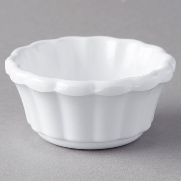 A white Carlisle ramekin with a scalloped edge on a gray surface.