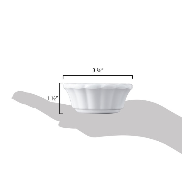 A hand holding a small white Carlisle scalloped ramekin.