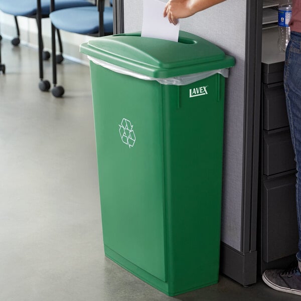 A woman standing next to a green Lavex recycle bin.