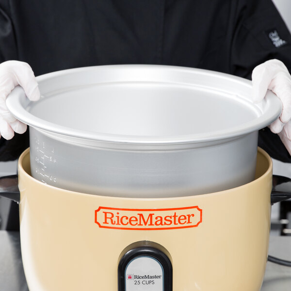 A person holding a large rice cooker pot.