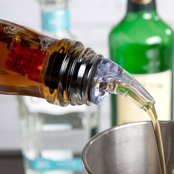 A person using a Tablecraft Proper Pour clear spout to pour liquid into a glass.