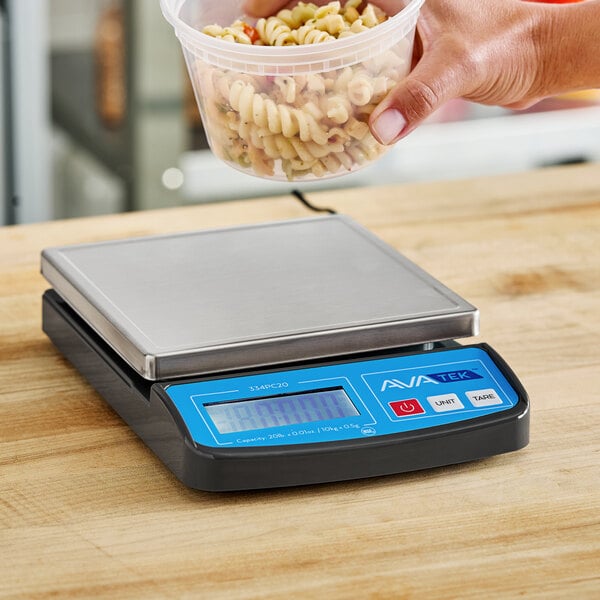 A person weighing a plastic container of pasta on an AvaWeigh digital scale.