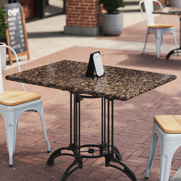 A table with an Art Marble Furniture Tan Brown Granite tabletop on a patio with chairs.