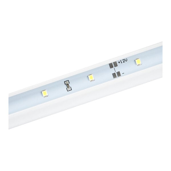 A close-up view of a strip with small LED lights and labeled electrical contacts.