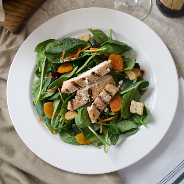 A Villeroy & Boch white porcelain round platter with a salad of chicken and vegetables.