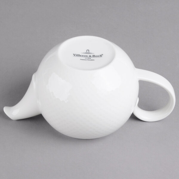 A white porcelain teapot with a handle.