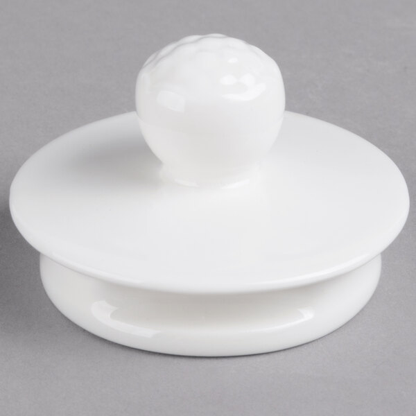 A white porcelain teapot lid with a white ball on top.