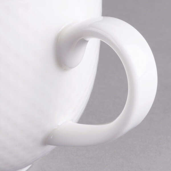 A close-up of a Villeroy & Boch white porcelain cup with a handle.
