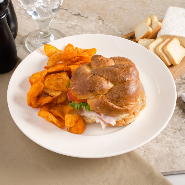 A Villeroy & Boch white porcelain plate with a sandwich and potato chips.
