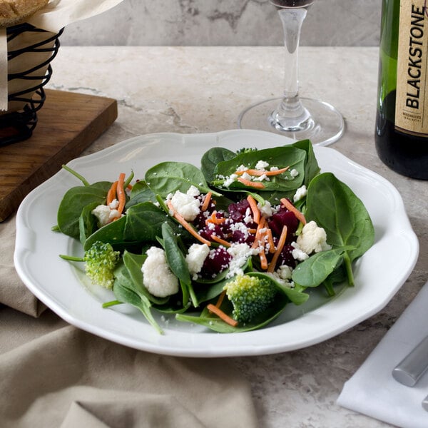 A Villeroy & Boch white porcelain plate with a vegetable salad and a glass of wine on a table.