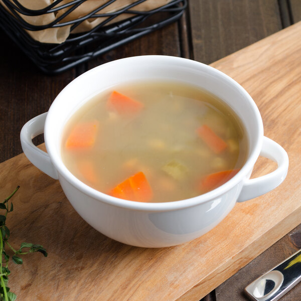 A white Villeroy & Boch porcelain soup cup with soup and vegetables in it.