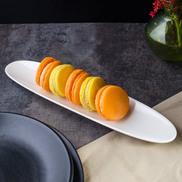 A white Villeroy & Boch porcelain boat filled with colorful macarons on a table.