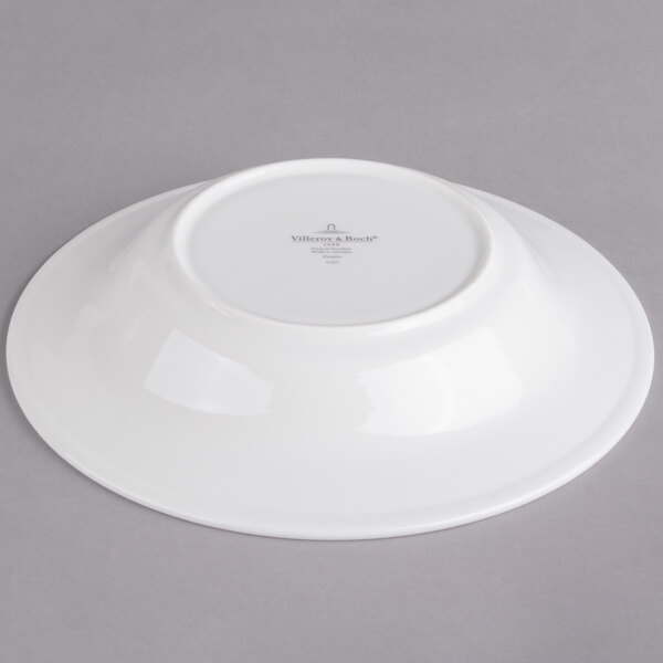 A white porcelain soup plate with a white rim on a gray surface.