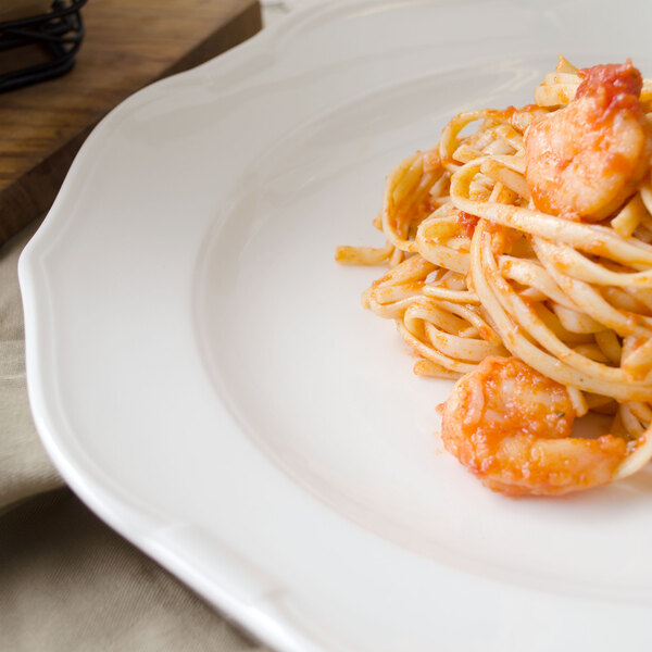 A Villeroy & Boch white porcelain flat plate with a plate of pasta and shrimp on it.