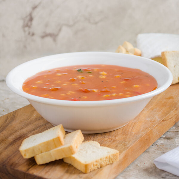 A bowl of soup with bread on a wood surface.