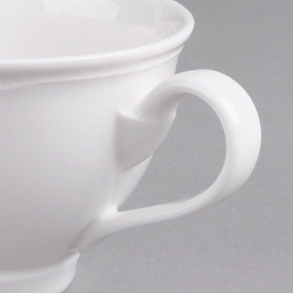 A close-up of a Villeroy & Boch white porcelain cup with a handle.