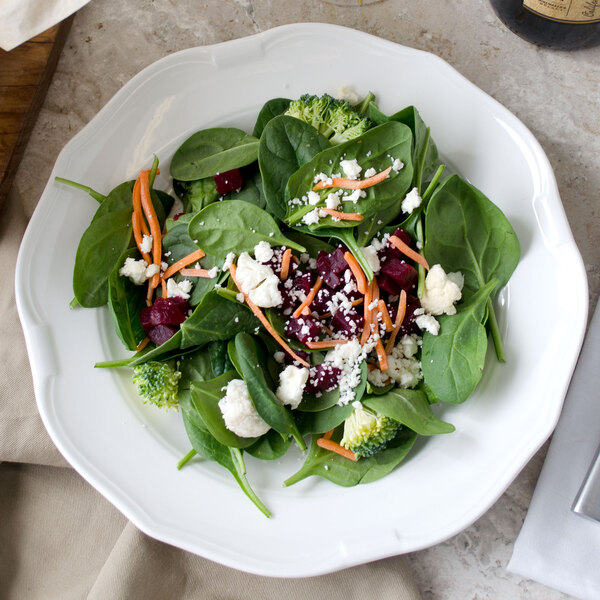 A Villeroy & Boch white porcelain plate with a salad of spinach, carrots, and cheese.