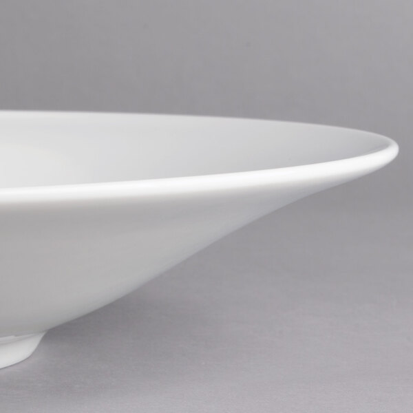 A close-up of a Villeroy & Boch white porcelain coupe deep plate with a rim.