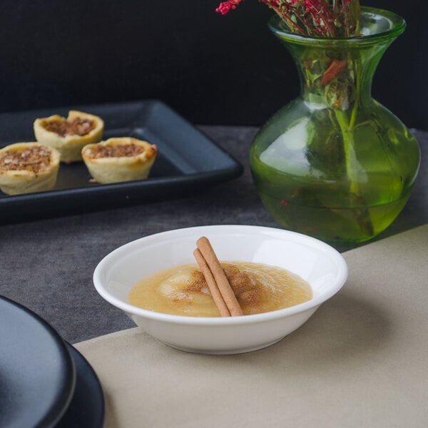 A bowl of food with cinnamon sticks on a table next to a vase of flowers.