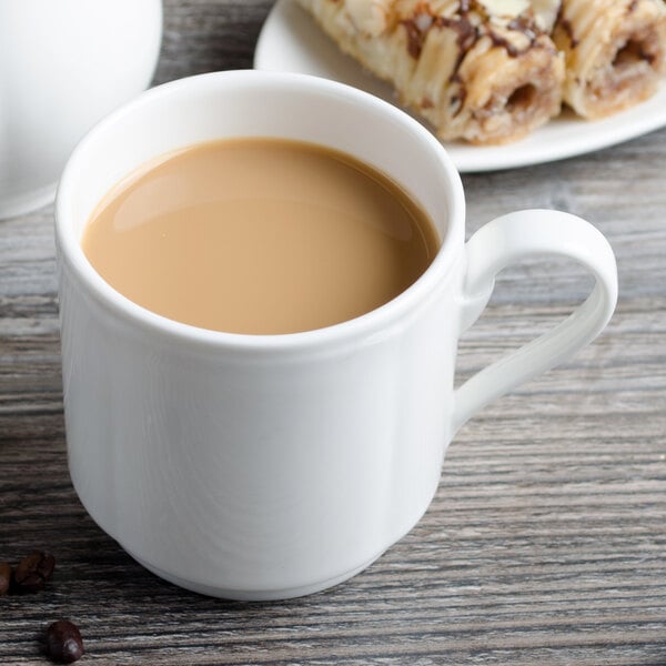 A Villeroy & Boch white porcelain mug with coffee on a saucer with pastries.