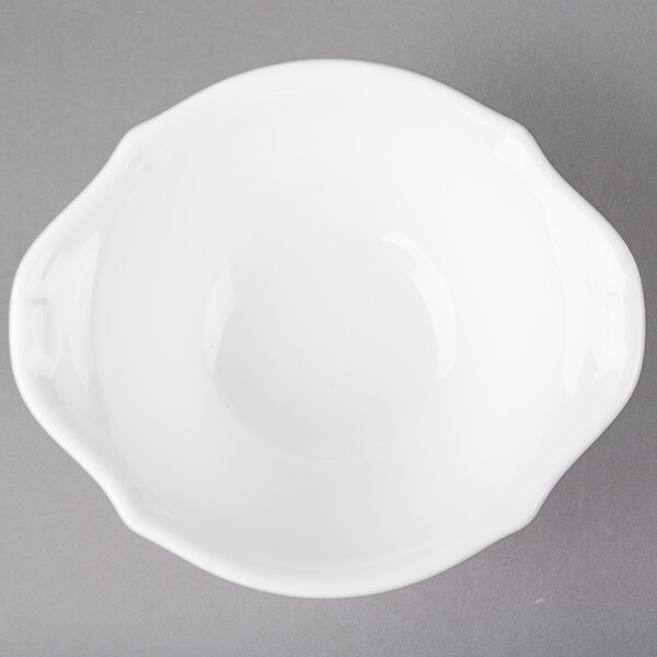 A white bowl with a handle on a gray surface.
