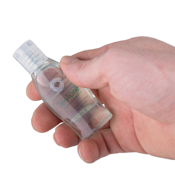 A hand holding a small Dial Restore body wash bottle.
