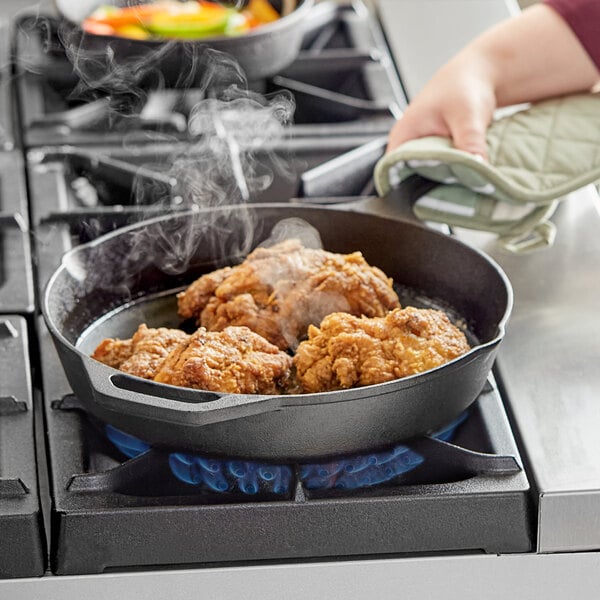 fried chicken frying in a cast iron plan on a range stove