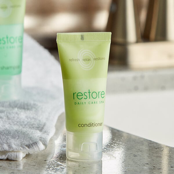 A small green Dial Restore conditioner bottle with green text.