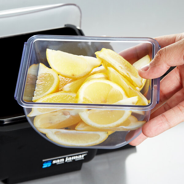 A hand holding a San Jamar standard tray with lemon slices in it.
