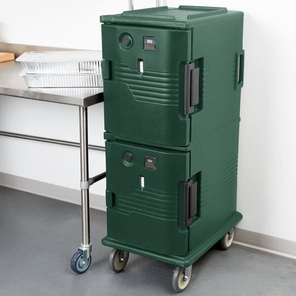 A green Cambro Ultra Camcart holding a green plastic box on a cart.