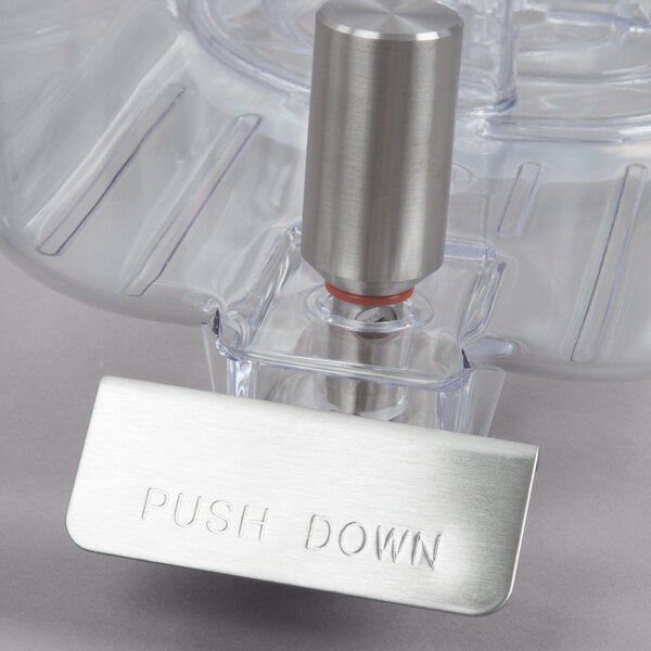A close up of the push down device on a Crathco refrigerated beverage dispenser.