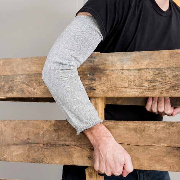A man wearing a Cordova Monarch cut-resistant sleeve holding a wooden pallet.