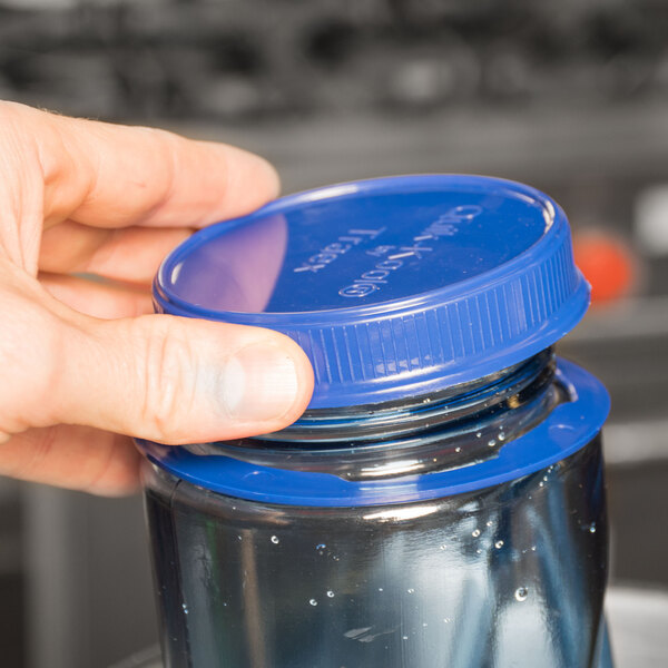 A hand holding a blue Tethered Cooling Paddle Cap on a plastic jar.