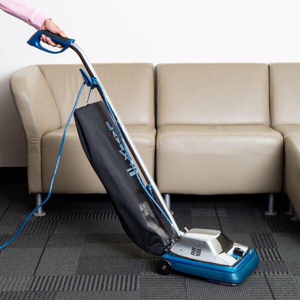Someone using a vacuum cleaner on a black rug