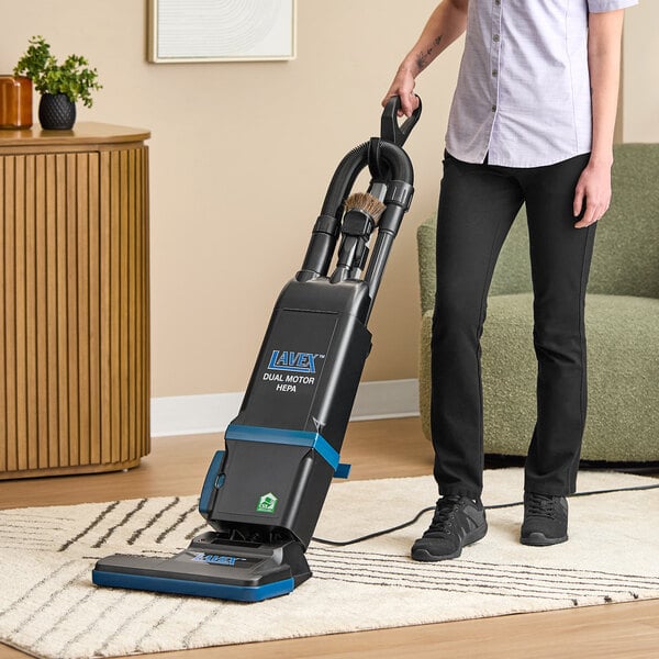 A person using a Lavex 15-inch dual motor upright bagged vacuum cleaner with HEPA filtration on a carpet.