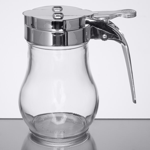 A Tablecraft glass syrup dispenser with a chrome-plated metal lid and handle.