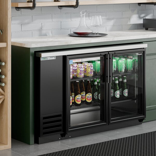 A black glass door back bar refrigerator with LED lighting, stocked with bottles and cans.