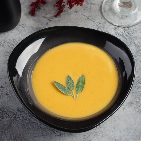 A black Reserve by Libbey Pebblebrook porcelain bowl filled with soup and sage leaves.