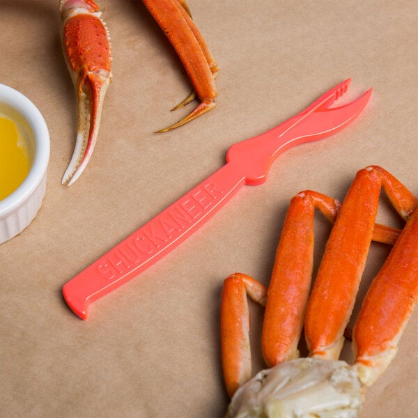 A Choice pink seafood sheller next to crab claws on a table.