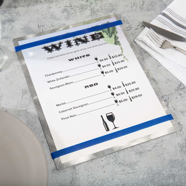 An Alumitique menu board with navy bands on a table with silverware and a wine menu.