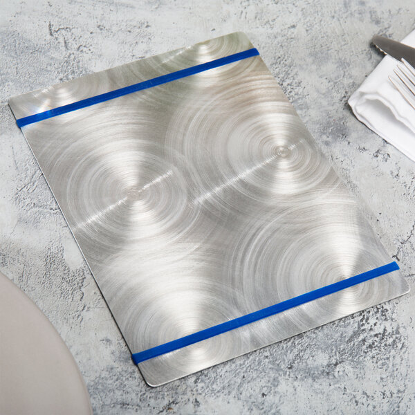 A silver Alumitique menu board with navy blue bands on a table.