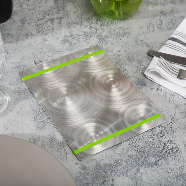 An Alumitique menu board with green bands on a table with a knife and fork